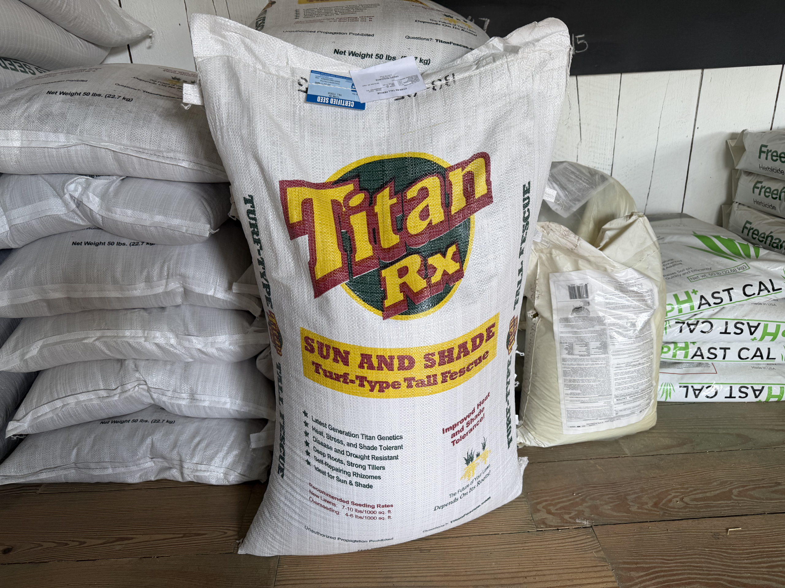 A bag of grass seed stacked in front of pallets of bags of seed.