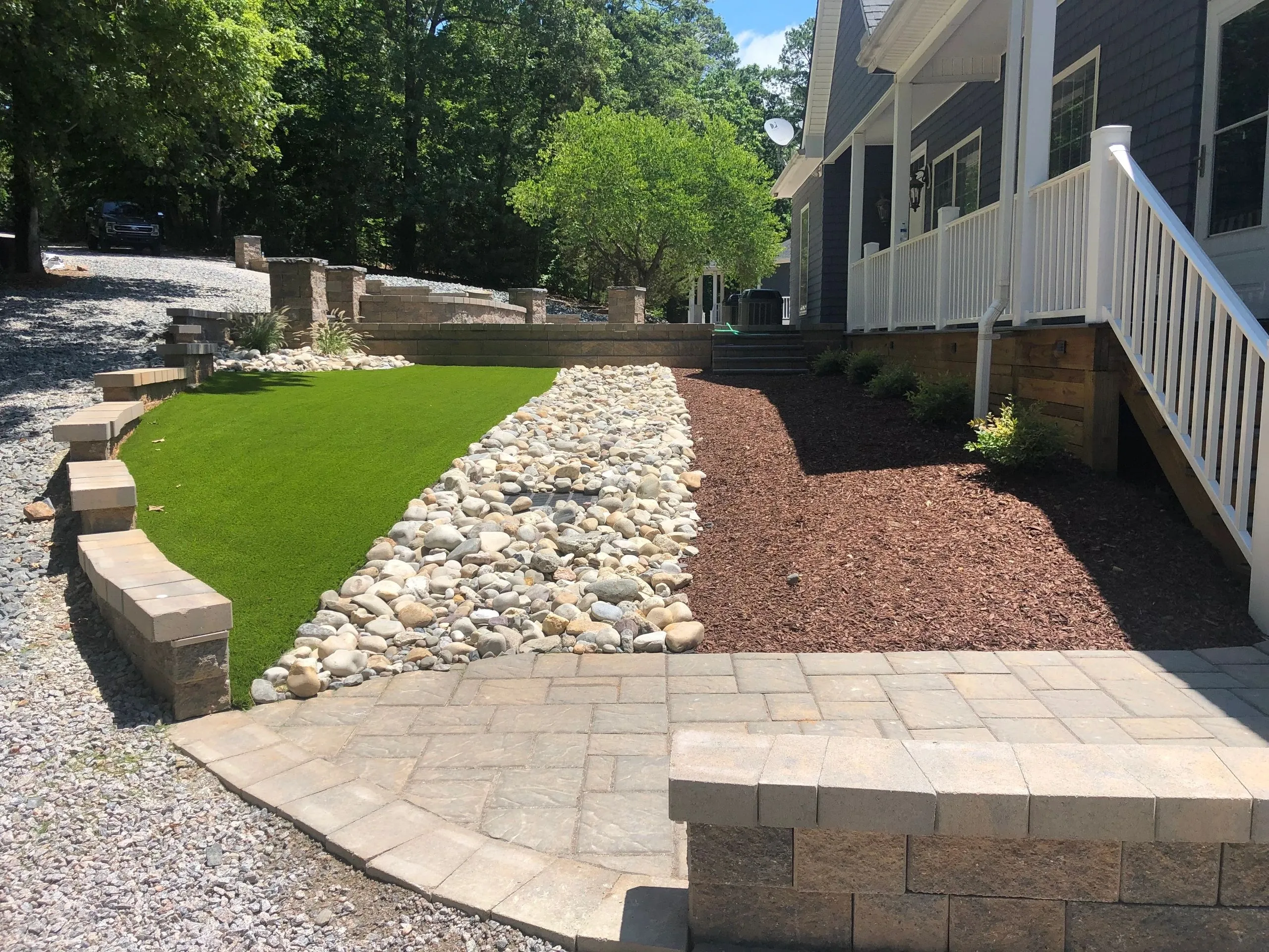 A landscaped lawn with grass, white stone, and brown mulch
